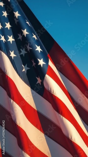 Majestic american flag waving gracefully against blue sky background.