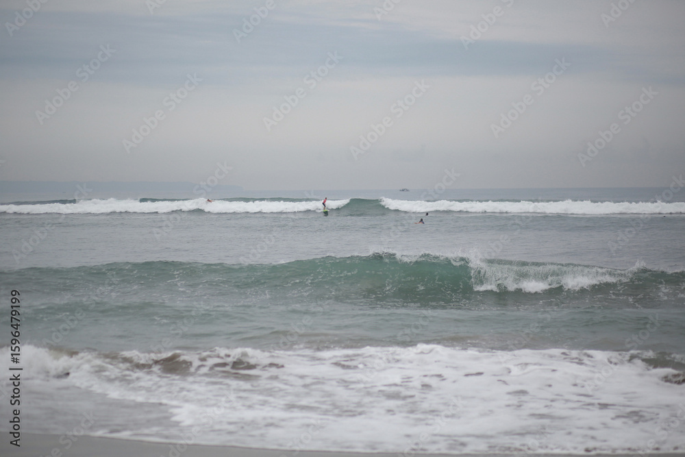 Surfers Riding Waves in the Ocean on a Sunny Day Surfers Riding Waves in the Ocean on a Sunny Day