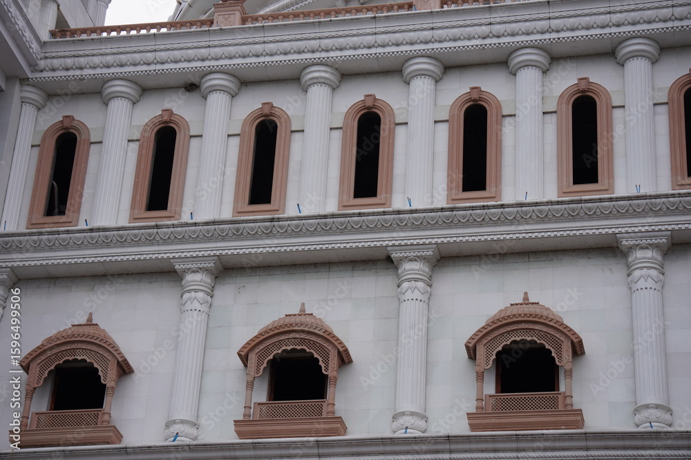 Fototapeta premium Classical European Facade with Arched Windows, Ornate Columns, and Pink Accents