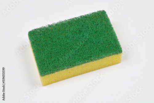 A new, yellow and green dish scrubbing sponge on a white surface