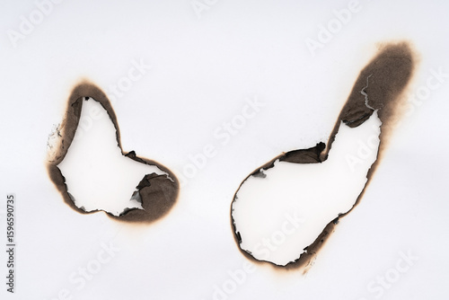 Burnt hole isolated on white paper. burns borders paper close up. Paper burn black stain mark close up.