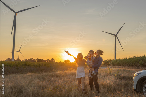 Family with son walking on field on wind farm. Happy Family and son playing at the Wind turbines generating electricity. Family time together.