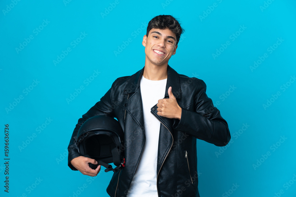 Young man with a motorcycle helmet over isolated blue background giving a thumbs up gesture Young man with a motorcycle helmet over isolated blue background giving a thumbs up gesture