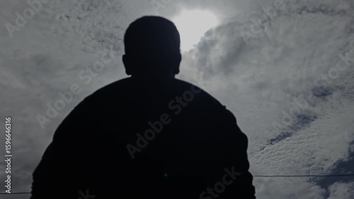 silhouette of a man looking up at the sky with the sunlight from the clouds, slow motion, 4K, Bright Sun light, Nature and Mental health, B-Roll Footage Inspirational and Motivational background.