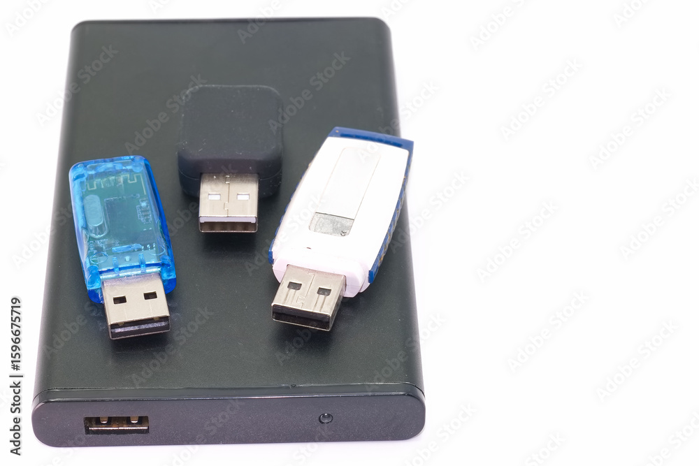 Fototapeta premium Small portable hard drive with multiple USB flash drives arranged on top in a bright light environment