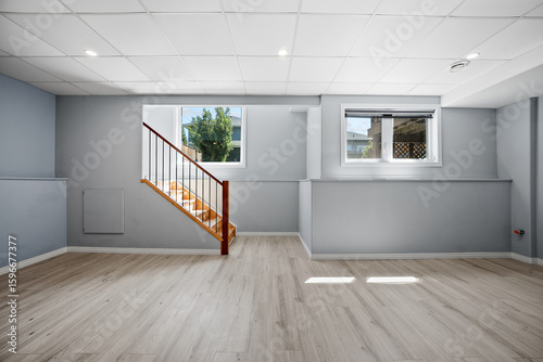 Large, empty room with a staircase and a window