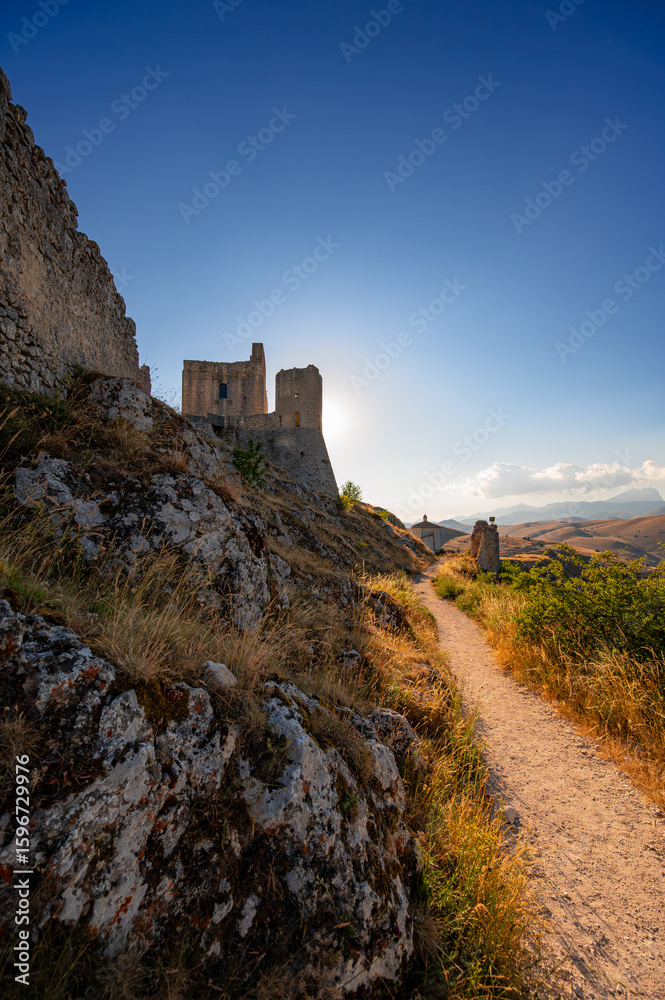 Fototapeta premium Italy, July 5, 2025: Ruins of Rocca Calascio Castle, an Italian tourist destination and landmark in the Gran Sasso National Park, L'Aquila, Abruzzo. Clear blue skies at sunset.
