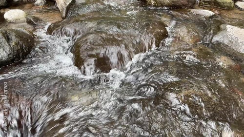 Clear mountain river water flows swiftly between large rocks, top view. Clear mountain river water. The water flows in waves. Splash of river water. Natural river views in the countryside.