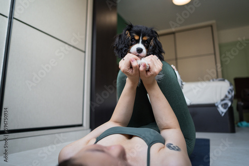 Young woman exercising at home with playful dog interruption