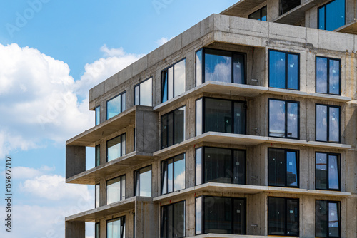 Residential building under construction with exposed concrete and glass windows