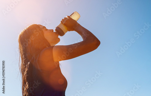 Female athlete refreshing and hydrating during a sunny summer workout