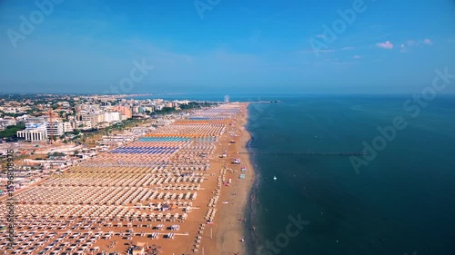 Aerial view of large equipped sandy beaches. Umbrellas and sun loungers for vacationers by the sea. Vacation on the Adriatic Sea. Ferris wheel. Traveling on Europe. Vacation in Italy Rimini 21.07.2025