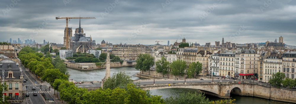 Fototapeta premium Paris, France - 07 19 2025: Notre Dame de Paris. Panoramic view of Notre-Dame cathedral, The Seine and La Defense district from the top of Arab World Institute