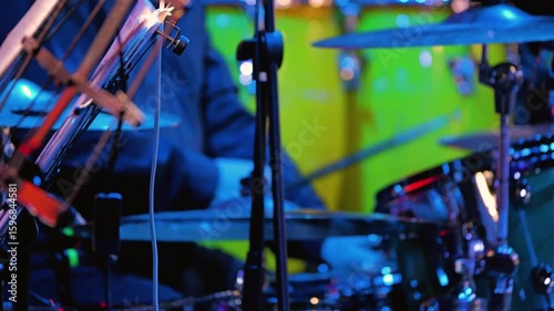 Close-up of a drummer playing the drums. The dynamic energy of a live performance, against a backdrop of bright lights and instruments