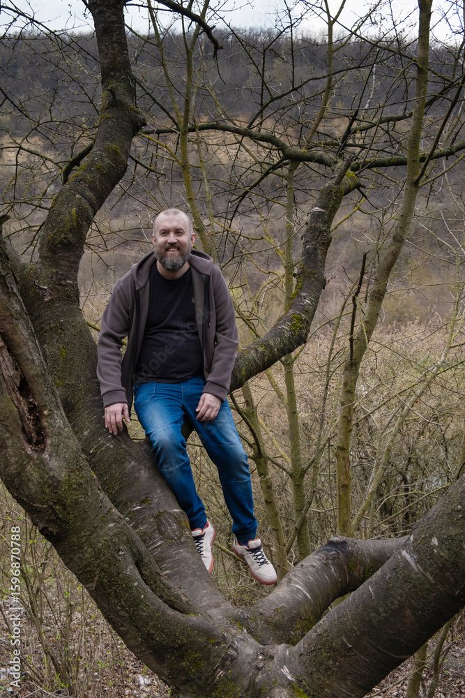 Naklejka premium Man with beard seats on old big tree