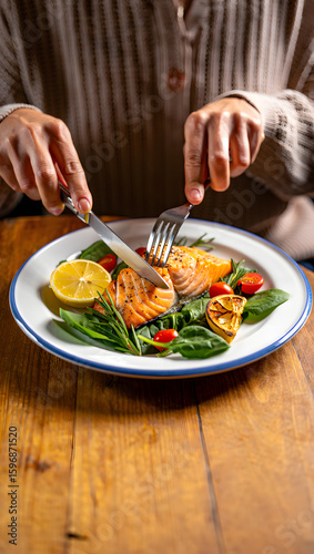 Wallpaper Mural Woman's hands cutting delicious grilled salmon fillet with lemon and spinach on rustic wooden table. Torontodigital.ca