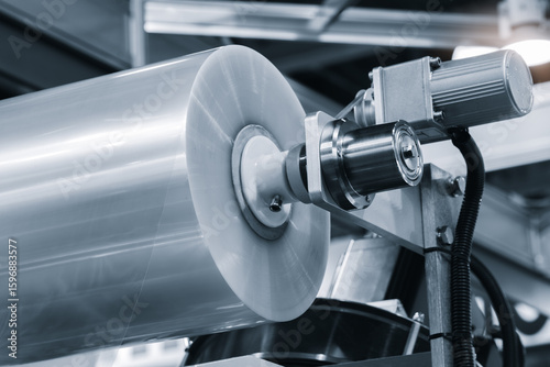 A machine with a roll of polyethylene plastic wrapping film on it. The machine is in a factory. industrial food packaging concept background
