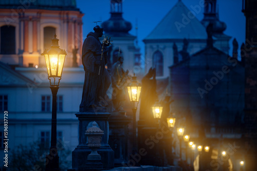 Early morning atmosphere of the famous Charles Bridge in Prague with the gas lamps lit.