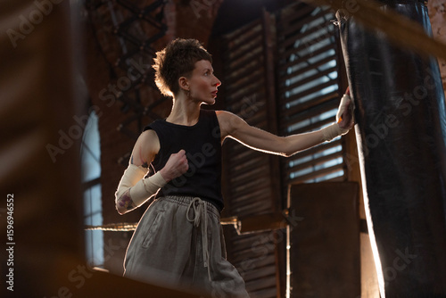 Short-haired boxer pausing workout, leaning on ring ropes with cinematic intensity