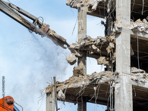 Heavy machinery demolishes a concrete structure at a construction site in broad daylight