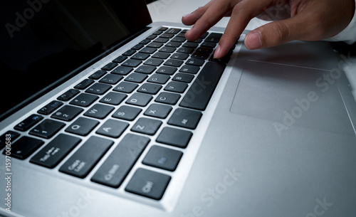 Businessman touching the keyboard of a laptop with his hands.