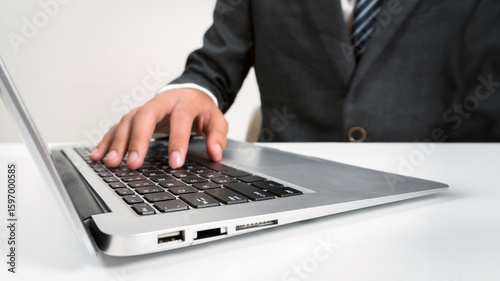 Businessman touching the keyboard of a laptop with his hands.