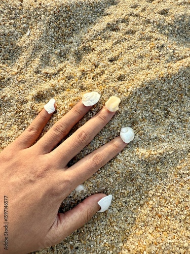 Hand with seashells as nails. hand on the beach sand