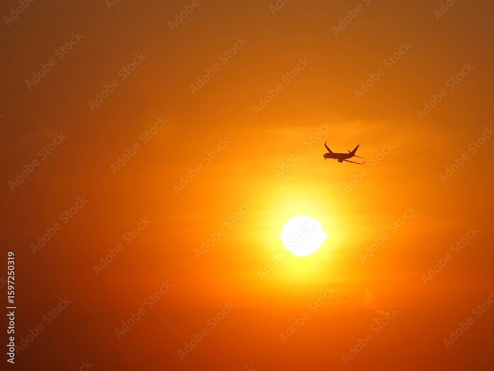Obraz premium Beautiful aerial view of orange sky and sun at outdoor with blurred background. Landscape panorama photography concept design at airport. Silhouette of airplane at sunset time.