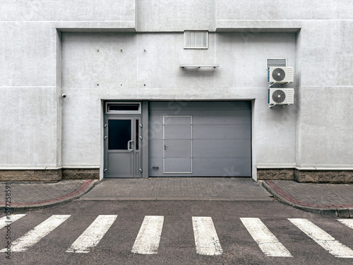 entrance of industrial building. closed metal rolling gate with door. front view.