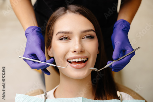 Happy patient during a visit to the dentist. The doctor is checking teeth using a dental instrument, ensuring proper oral care in the dentistry clinic