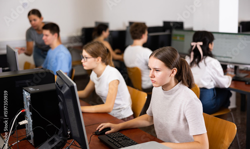 Photos Portrait of interested teen girl during lesson in computer room of school comput