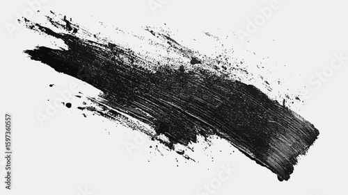 A rough black brush stroke with paint splatters isolated on white