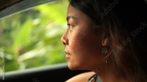 Smiling young Thai woman behind the wheel on scenic jungle road in Northern Thailand.