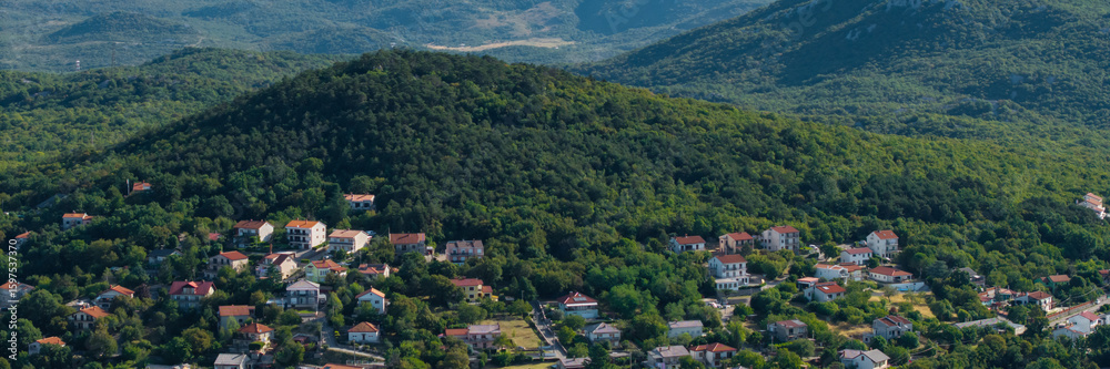 Fototapeta premium Panorama of elevated view of a traditional village nestled in a forested mountain landscape in Primorje-Gorski Kotar County, Croatia