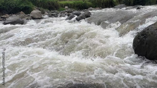Fast flowing mountain river with clear water rushing over large rocks and boulders. Clear and natural river water in the countryside. Scenic natural landscape in the countryside.