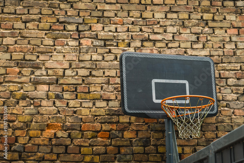Urban basketball hoop with weathered brick wall background under soft lighting, inviting spontaneous games and creativity