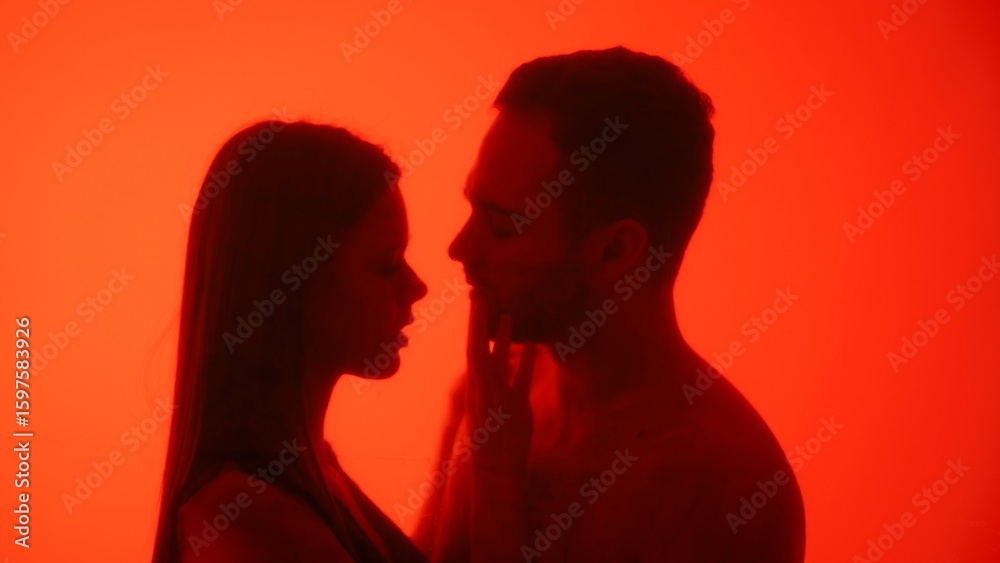 Fototapeta premium Silhouette of Couple Sharing an Intimate Moment in Red Light