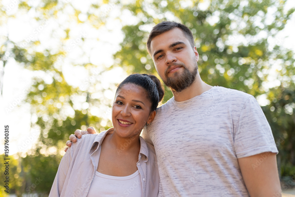Interracial couple smiling and embracing in a park Interracial couple smiling and embracing in a park