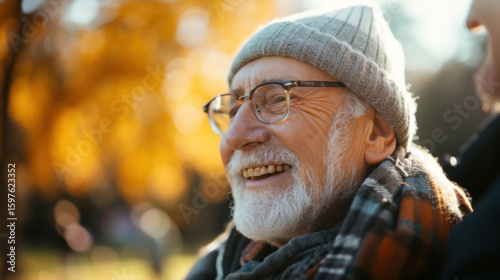 A cheerful senior man with a warm smile enjoying a sunny autumn day outdoors, showing positivity and joy.