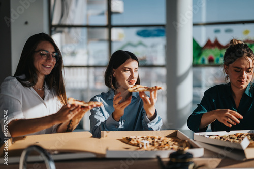 A group of colleagues sharing a pizza during a relaxed lunch break in a bright and modern office space, fostering team bonding and casual conversation.