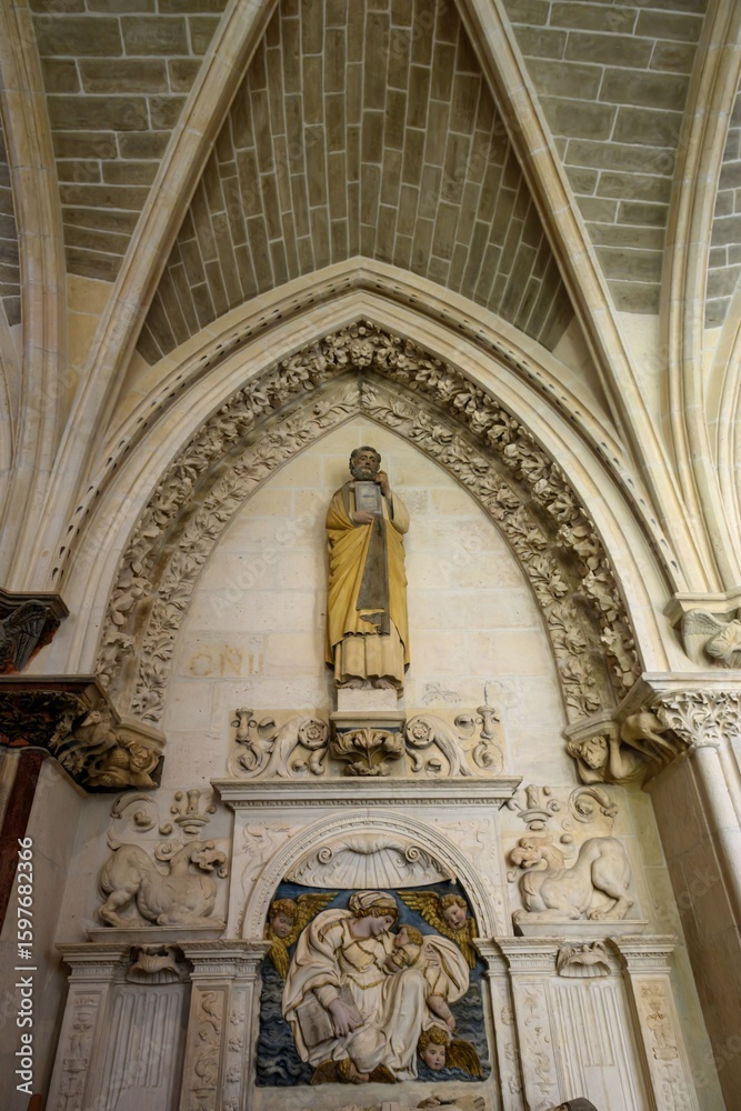 Fototapeta premium Saint Matthew statue above Renaissance tomb with angelic relief, in Burgos Cathedral.