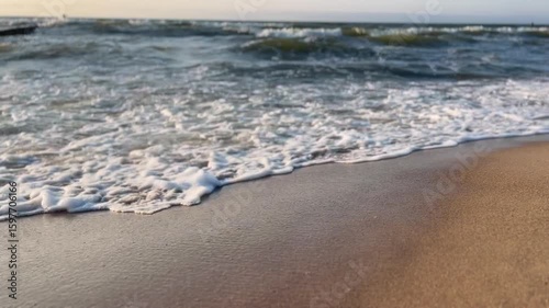 Golden sand beach with sea waves at sunset in Mielno, Baltic Sea coast, Poland