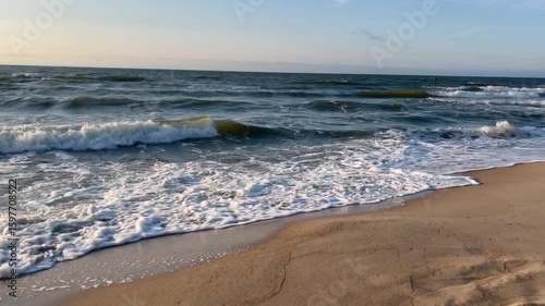 Golden sand beach with sea waves at sunset in Mielno, Baltic Sea coast, Poland