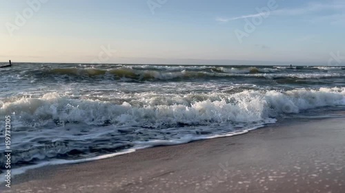Golden sand beach with sea waves at sunset in Mielno, Baltic Sea coast, Poland