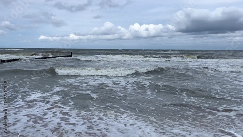Cloudy day at the Baltic Sea, stormy waves and breakwater on the shore