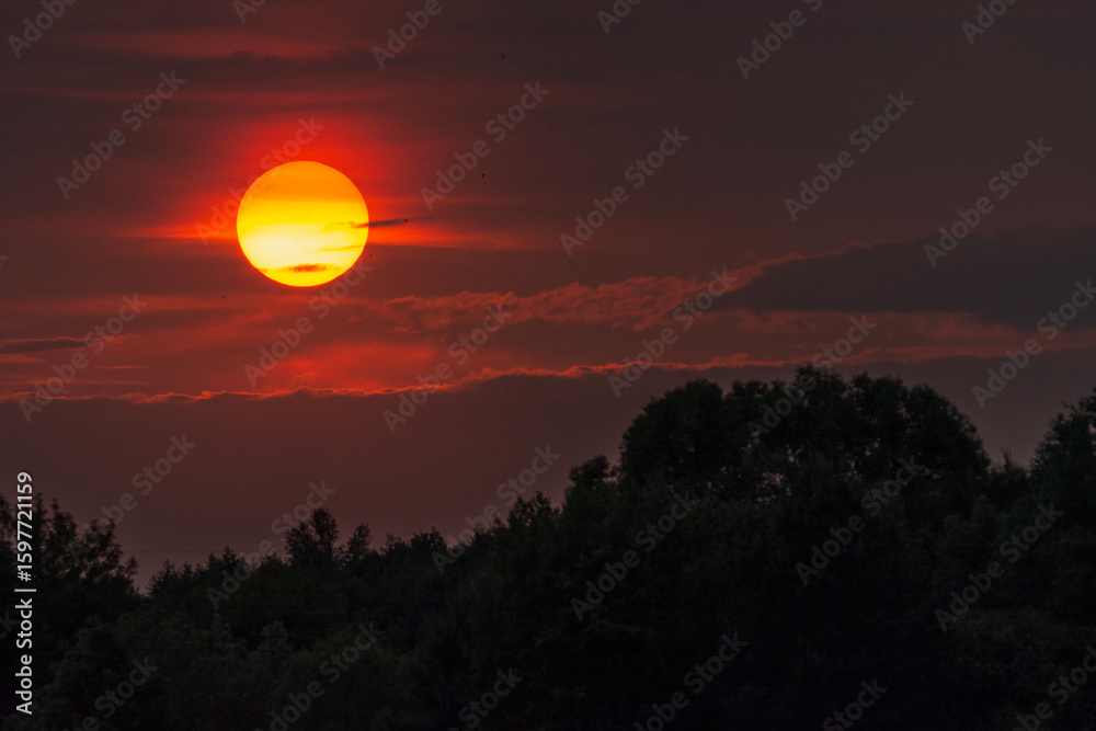 Obraz premium Big sun setting behind the clouds