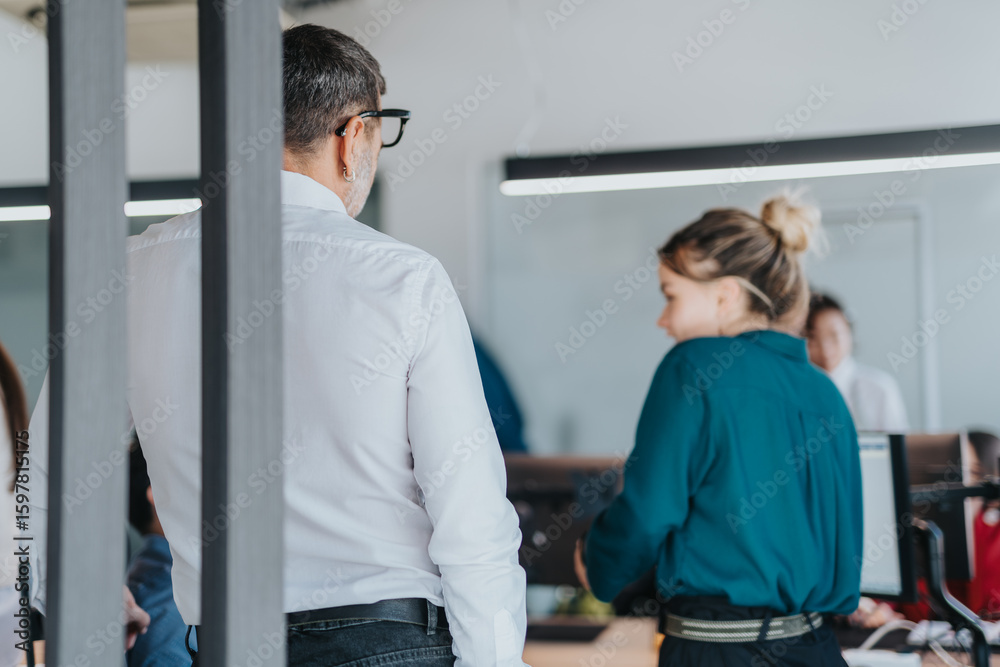 Obraz premium Two professional coworkers are seen engaging in a conversation. The modern office environment emphasizes collaboration, teamwork, and a professional atmosphere.