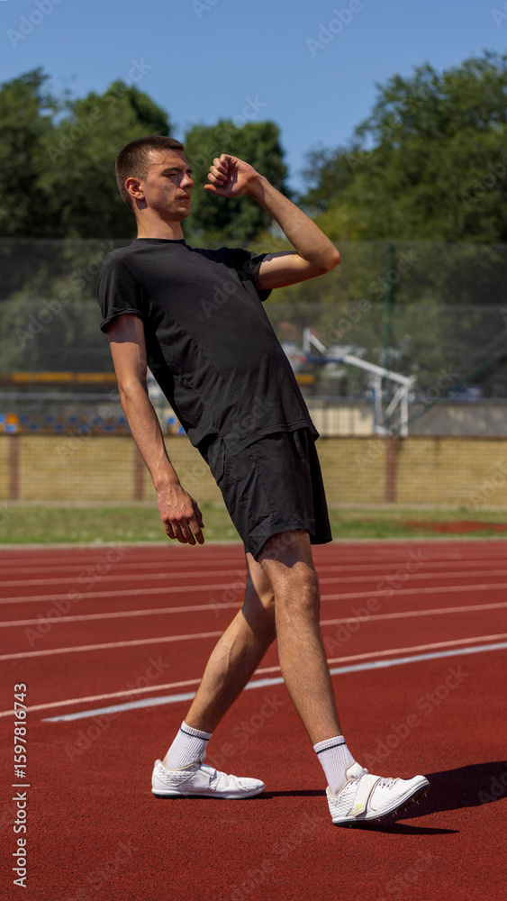 Obraz premium Athlete maintains balance on track beneath a sunny sky wearing casual sportswear. Concept of sportswear promo, posture detail, fitness clothing, active lifestyle and health-focused habits