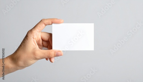 Mano de mujer sosteniendo una tarjeta blanca sobre fondo gris