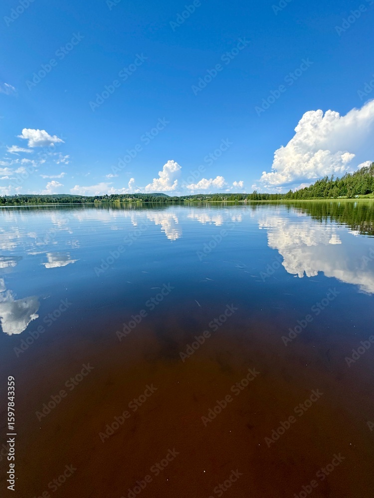 Fototapeta premium Tranquil Lake with Reflections and Blue Sky – Peaceful Nature Scene